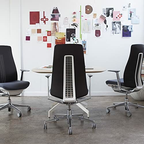 Modern office chairs around a table with creative wall display.