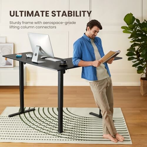 Man leaning on a modern standing desk with computer and notebook.