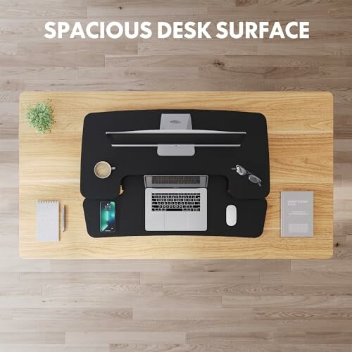 Top view of a desk with a laptop, mouse, phone, and plant.