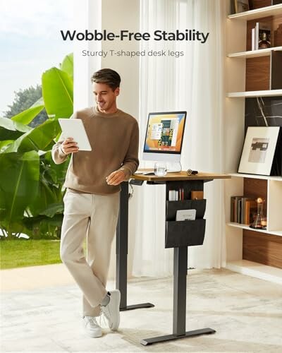 Man using a standing desk with T-shaped legs for stability.